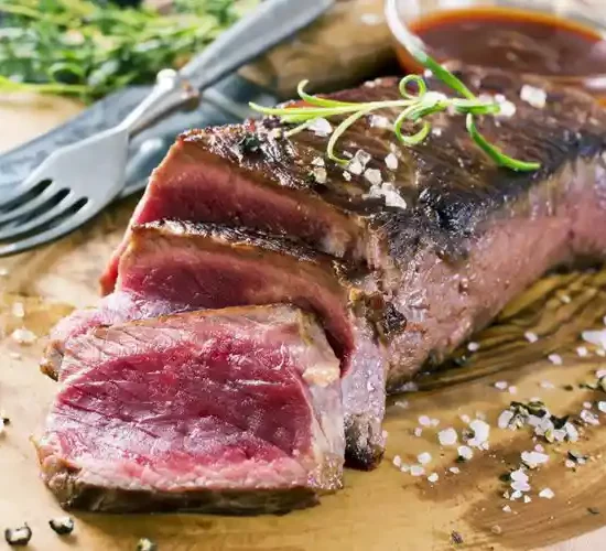 Viande rouge tranchée grillée servie sur planche au restaurant la Table de Trois à Bordeaux.